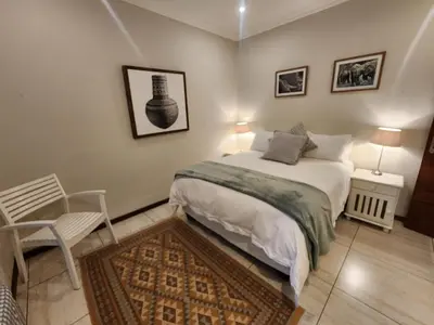 a small bedroom with a bed and a chair at Maclarty House - Golf Estate Villa in White River