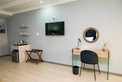 a room with a desk and a television on a wall at The Luthe in Thohoyandou