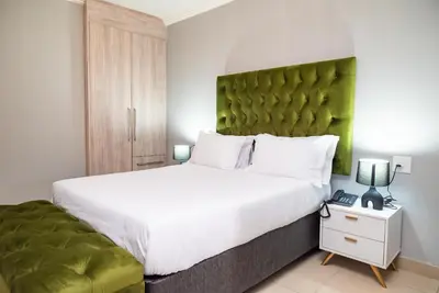 a bedroom with a large bed with a green headboard at The Luthe in Thohoyandou