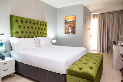 a bedroom with a large bed and a green headboard at The Luthe in Thohoyandou