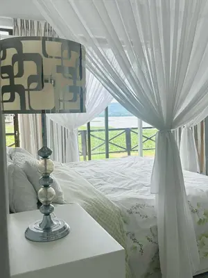 a bed with a canopy and a lamp on a table at View at 81 in Hartbeespoort