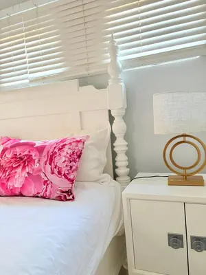 a white bed with a pink pillow and a nightstand at View at 81 in Hartbeespoort