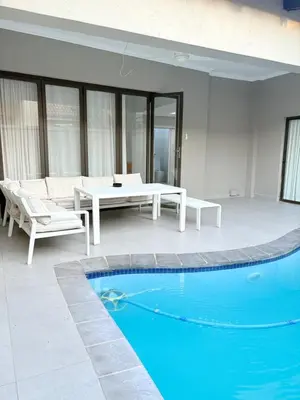 a patio with a pool and a table and a couch at View at 81 in Hartbeespoort