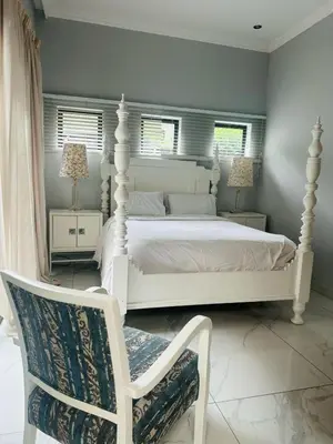 a bedroom with a white bed and a white chair at View at 81 in Hartbeespoort