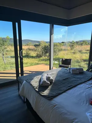 a bed in a room with a large window at Gweda Lodge in Ouklip