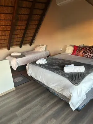 three beds in a room with wood floors at Gweda Lodge in Ouklip