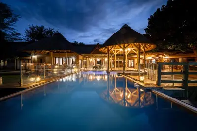 a swimming pool in front of a house at night at Xidulu Safari Lodge - Makalali in Makalali Game Reserve