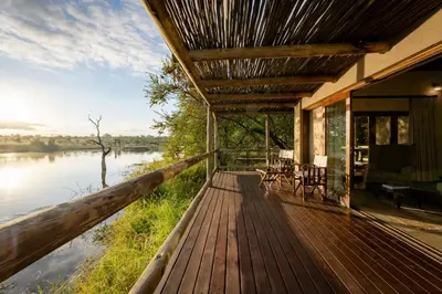 a house with a wooden deck next to a river at Xidulu Safari Lodge - Makalali in Makalali Game Reserve