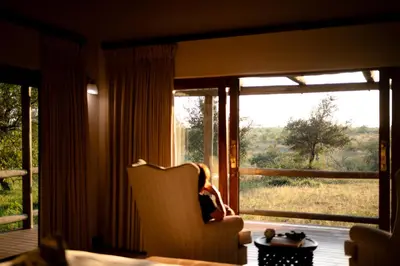 a woman sitting in a chair in front of a window at Xidulu Safari Lodge - Makalali in Makalali Game Reserve