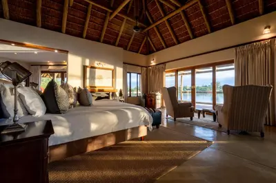a bedroom with a large bed with a view of the water at Xidulu Safari Lodge - Makalali in Makalali Game Reserve