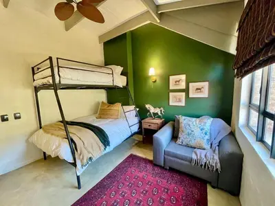 a bedroom with a bunk bed and a couch at Stone Creek Mountain Lodge in Dullstroom