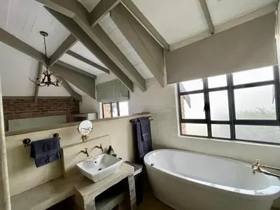 a bathroom with a white tub and a sink at Stone Creek Mountain Lodge in Dullstroom