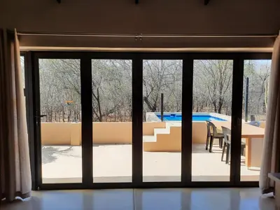 a sliding glass door with a view of a pool at Selfcatering accommodatie Villa BoerenBerg Marloth park, zuid Afrika in Marloth Park