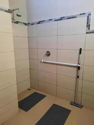 a shower in a bathroom with white tile walls at Selfcatering accommodatie Villa BoerenBerg Marloth park, zuid Afrika in Marloth Park