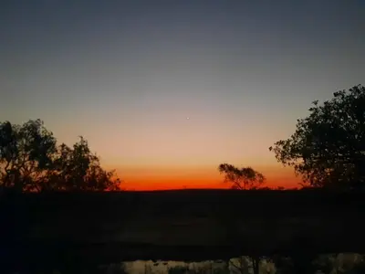 a sunset over a field with trees in the foreground at Selfcatering accommodatie Villa BoerenBerg Marloth park, zuid Afrika in Marloth Park