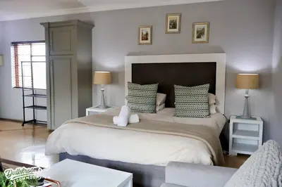 a bedroom with a large bed with green and white pillows at Cherry Grove 3 in Dullstroom