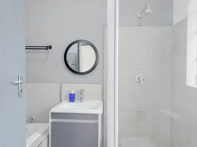 a white bathroom with a sink and a shower at Amoris Guesthouse - Hillcrest Brooklyn in Pretoria
