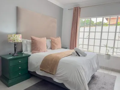 a bedroom with a large bed and a window at Amoris Guesthouse - Hillcrest Brooklyn in Pretoria