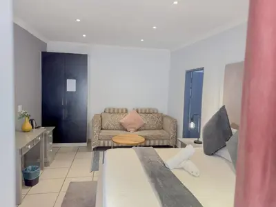 a living room with a bed and a couch at Amoris Guesthouse - Hillcrest Brooklyn in Pretoria