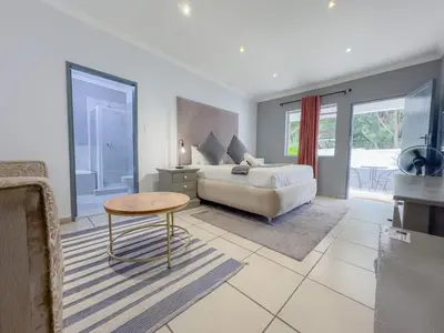 a living room with a bed and a table at Amoris Guesthouse - Hillcrest Brooklyn in Pretoria