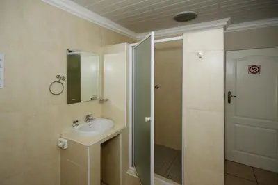 a bathroom with a sink and a shower with a mirror at Dormio Manor Guest Lodge in Secunda