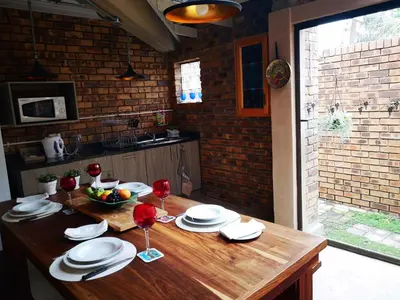 a wooden table with plates and wine glasses on it at Dormio Manor Guest Lodge in Secunda