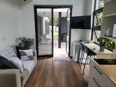 a living room with a couch and a kitchen at The Cottage in Secured Estate in Pretoria