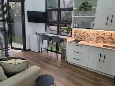 a living room with a couch and a kitchen at The Cottage in Secured Estate in Pretoria