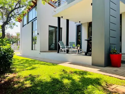 a house with a patio with a table and chairs at The Cottage in Secured Estate in Pretoria