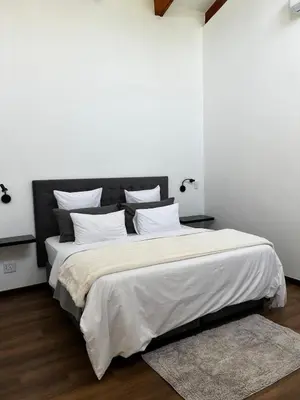 a bedroom with a large bed with white sheets and pillows at The Cottage in Secured Estate in Pretoria