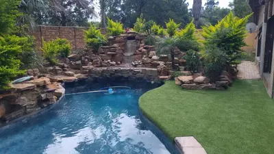 a swimming pool in a yard with a waterfall at Amani Peaceful Home in Centurion