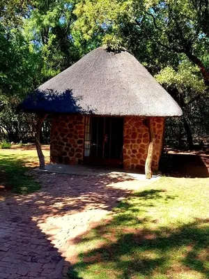 a small brick building with a straw roof at Thaba Tshwene Game Farm in Modimolle