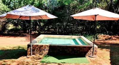 two umbrellas sitting next to a swimming pool at Thaba Tshwene Game Farm in Modimolle