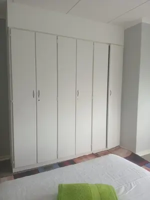 a bedroom with white cabinets and a bed with a green blanket at Inspire living home in Kempton Park