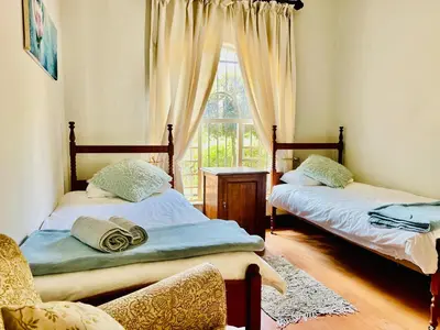 two beds in a room with a window at Patches Place in Pretoria