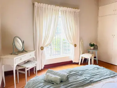 a bedroom with a bed and a mirror and a window at Patches Place in Pretoria