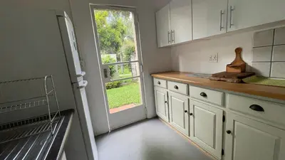 a kitchen with white cabinets and an open door at Patches Place in Pretoria