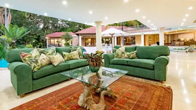 a living room with green couches and a glass table at Villa Christies at 32 on Russell in Nelspruit
