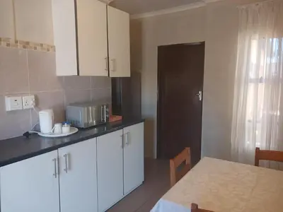 a kitchen with white cabinets and a table and a door at AS contractors accommodation in Erasmus