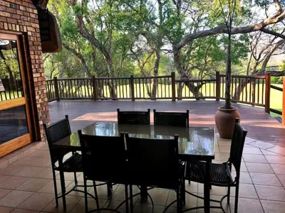 a glass table and chairs on a patio at Ezulwini - Kruger Park Lodge Golf Estate in Hazyview