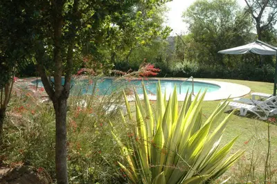 a swimming pool with an umbrella and a table and chairs at Ezulwini - Kruger Park Lodge Golf Estate in Hazyview