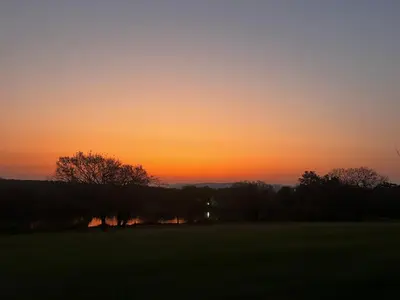 a sunset over a field with trees in the foreground at Ezulwini - Kruger Park Lodge Golf Estate in Hazyview