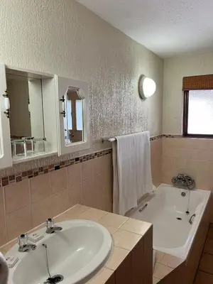 a bathroom with a sink and a tub and a mirror at Ezulwini - Kruger Park Lodge Golf Estate in Hazyview