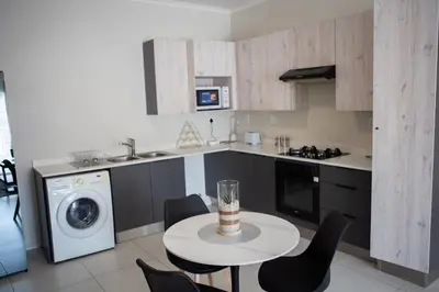 a kitchen with a table and chairs and a washer at Oasis Comfort Apartment in Midrand