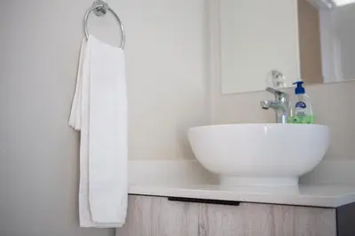 a bathroom with a white sink and a white towel at Oasis Comfort Apartment in Midrand