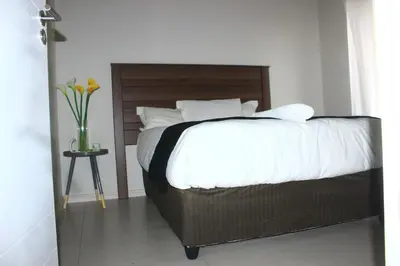 a bed with a wooden headboard and a vase of flowers at Oasis Comfort Apartment in Midrand