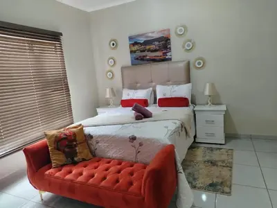 a bedroom with a bed and a red couch at Fairy Gardens Lodge in Pretoria
