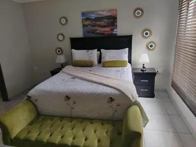 a bedroom with a large bed with a green couch at Fairy Gardens Lodge in Pretoria