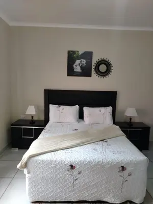 a bedroom with a large bed with two night stands at Fairy Gardens Lodge in Pretoria