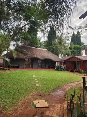 a building with a grass yard in front of it at Fairy Gardens Lodge in Pretoria